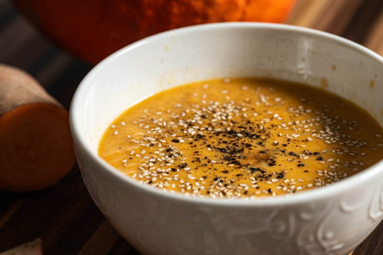 gallery-2 Warm pumpkin soup garnished with sesame seeds and pepper, perfect for a cozy meal.